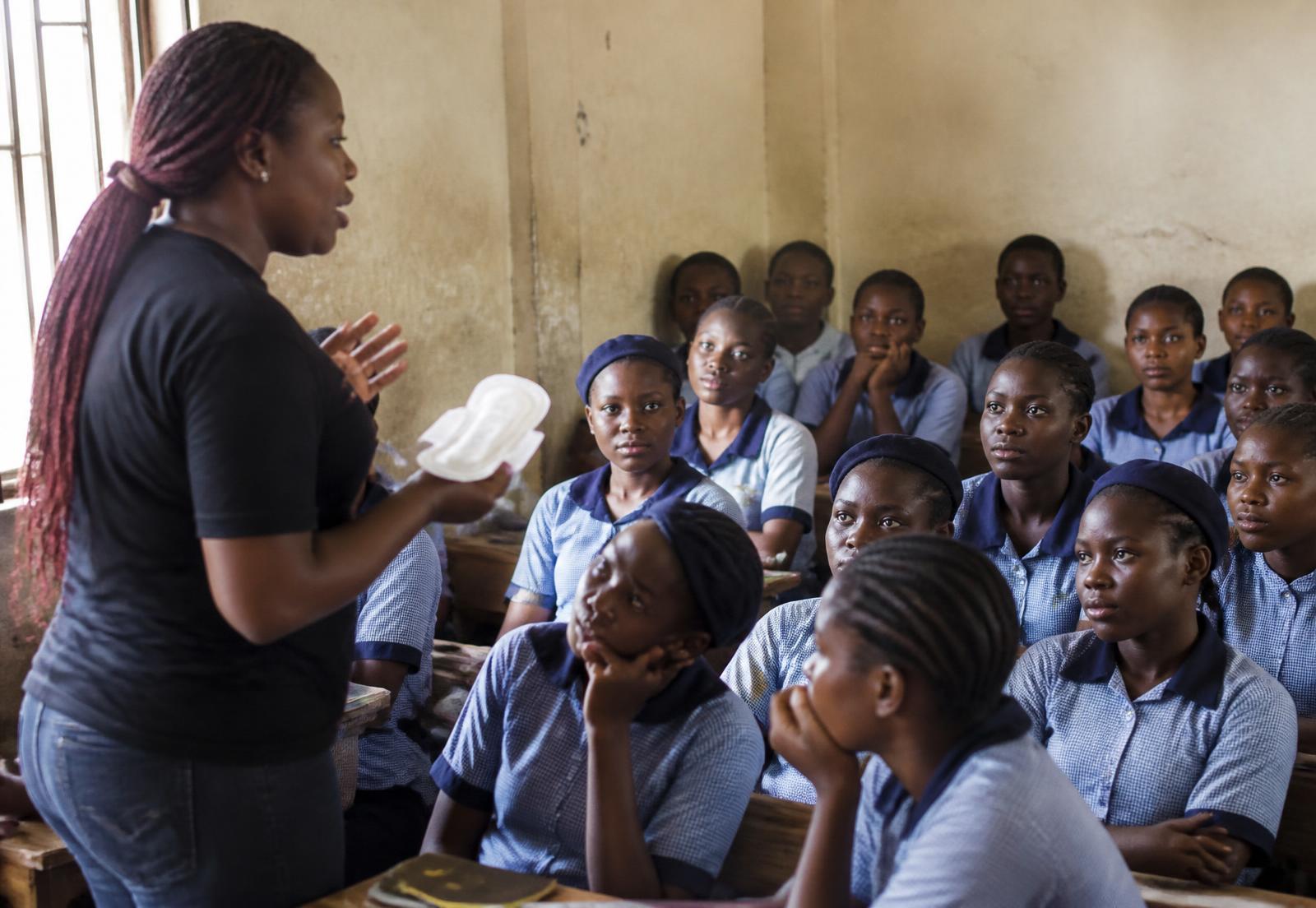 A health educator holding a sanitary pad while speaking to a classroom of Nigerian schoolgirls