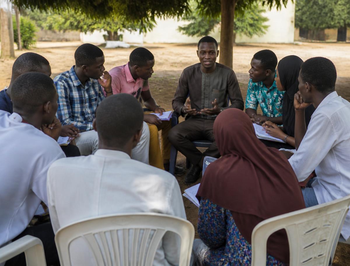 Young Nigerian people seated in a circle during an outdoor mentorship session